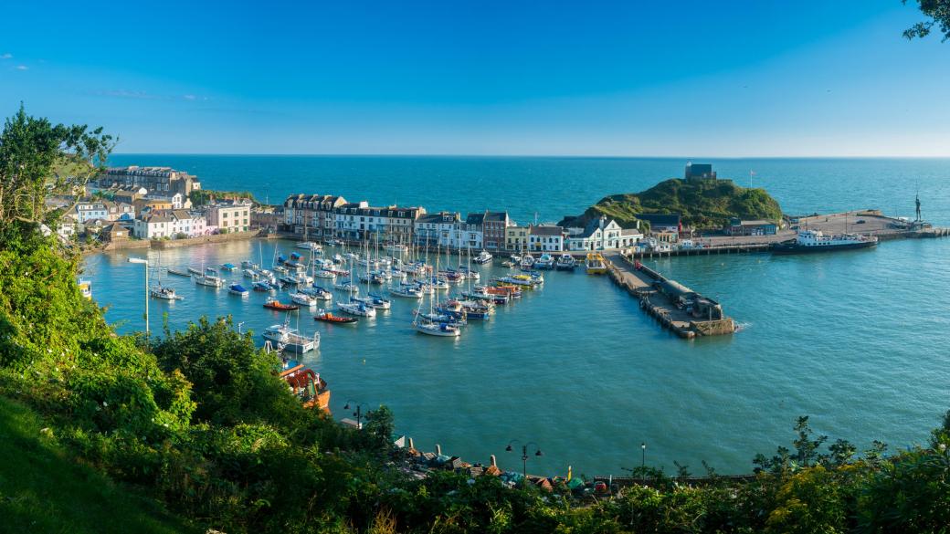 Ilfracombe Harbour at sunrise in broad panorama across the picturesque town.