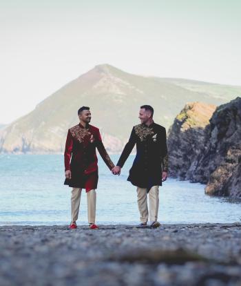 A couple walking on Broadsands beach near Sandy Cove Hotel after their wedding ceremony