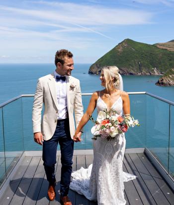 A bride and groom standing on the platform overlooking the bay on their Wedding day at Sandy Cove Hotel's The Venue