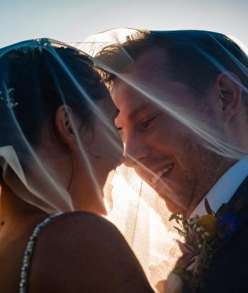 A bride and groom about to share a kiss under the bride's veil at Sandy Cove Hotel