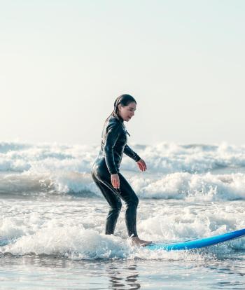 Female surfer riding a small wave on a North Devon beach
