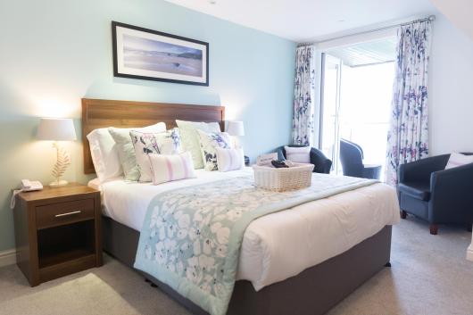 A bed with lamps inside a balcony room at Sandy Cove Hotel