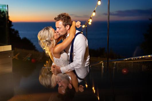 Bride and groom kiss in front of sunset