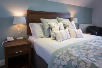 Cushions and pillows on the bed inside a Superior Sea View with Balcony room at Sandy Cove Hotel