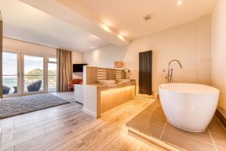 The interior of a luxury sea view room at Sandy Cove Hotel showing the in-room bathtub and balcony